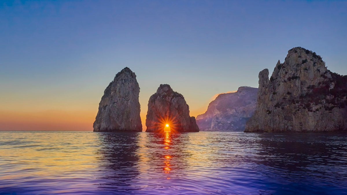 Sunset through the arch of Capri's Farafliones.